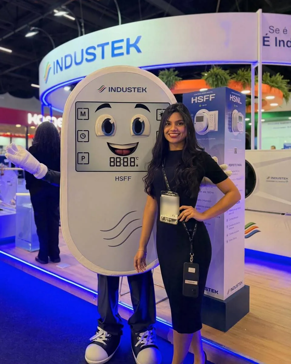 Profissional vestido de mascote ao lado de promotora no estande da Industek em feira