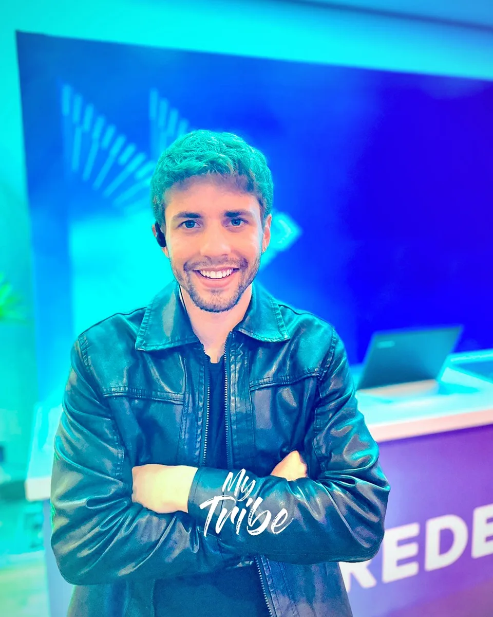 Produtor de eventos sorrindo com ponto de comunicação no ouvido, em frente ao balcão de um evento
