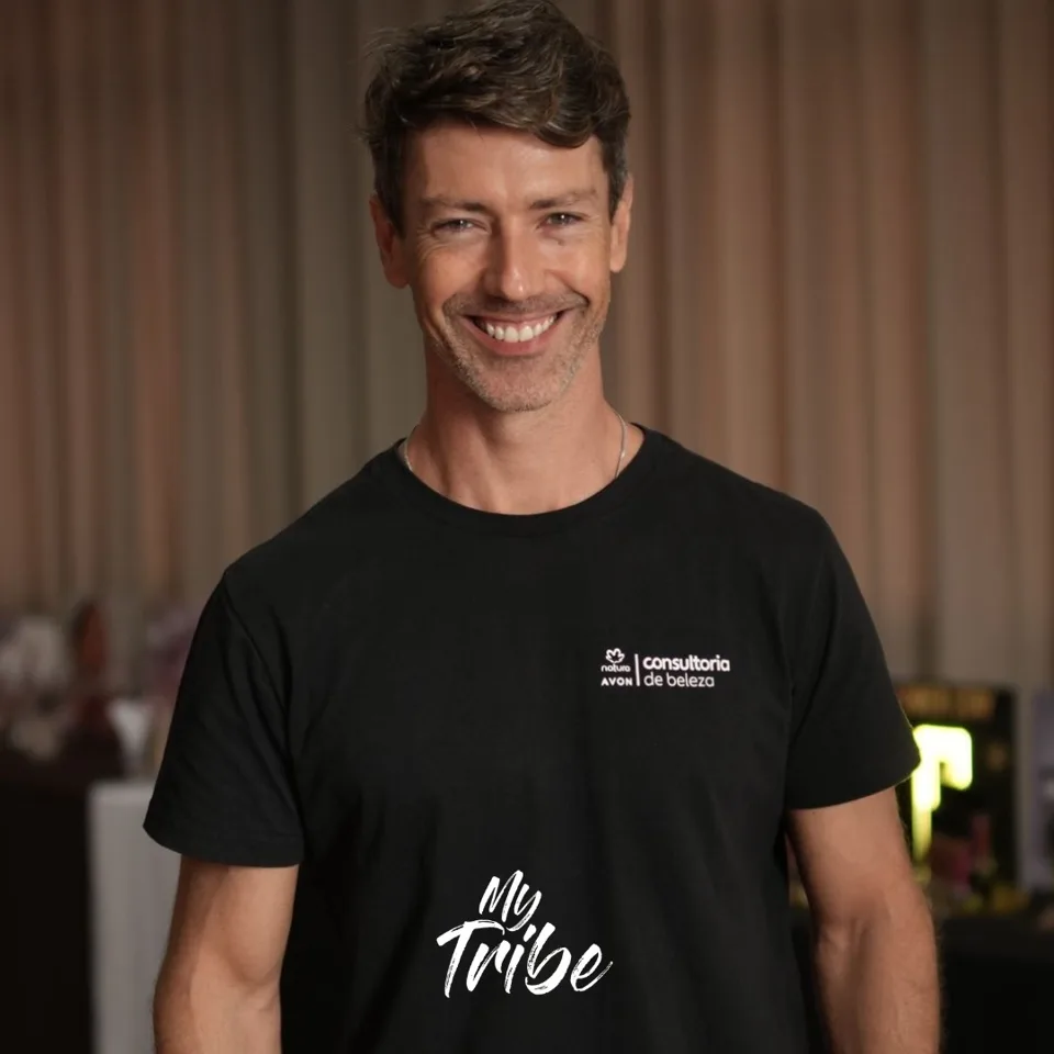 Produtor sorrindo com camiseta da consultoria de beleza Natura Avon em evento corporativo