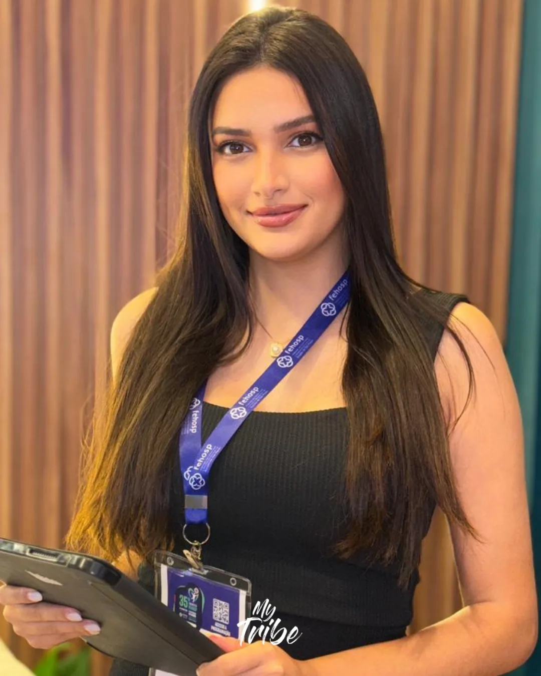 Promotora de eventos sorrindo com tablet na mão no credenciamento de um congresso