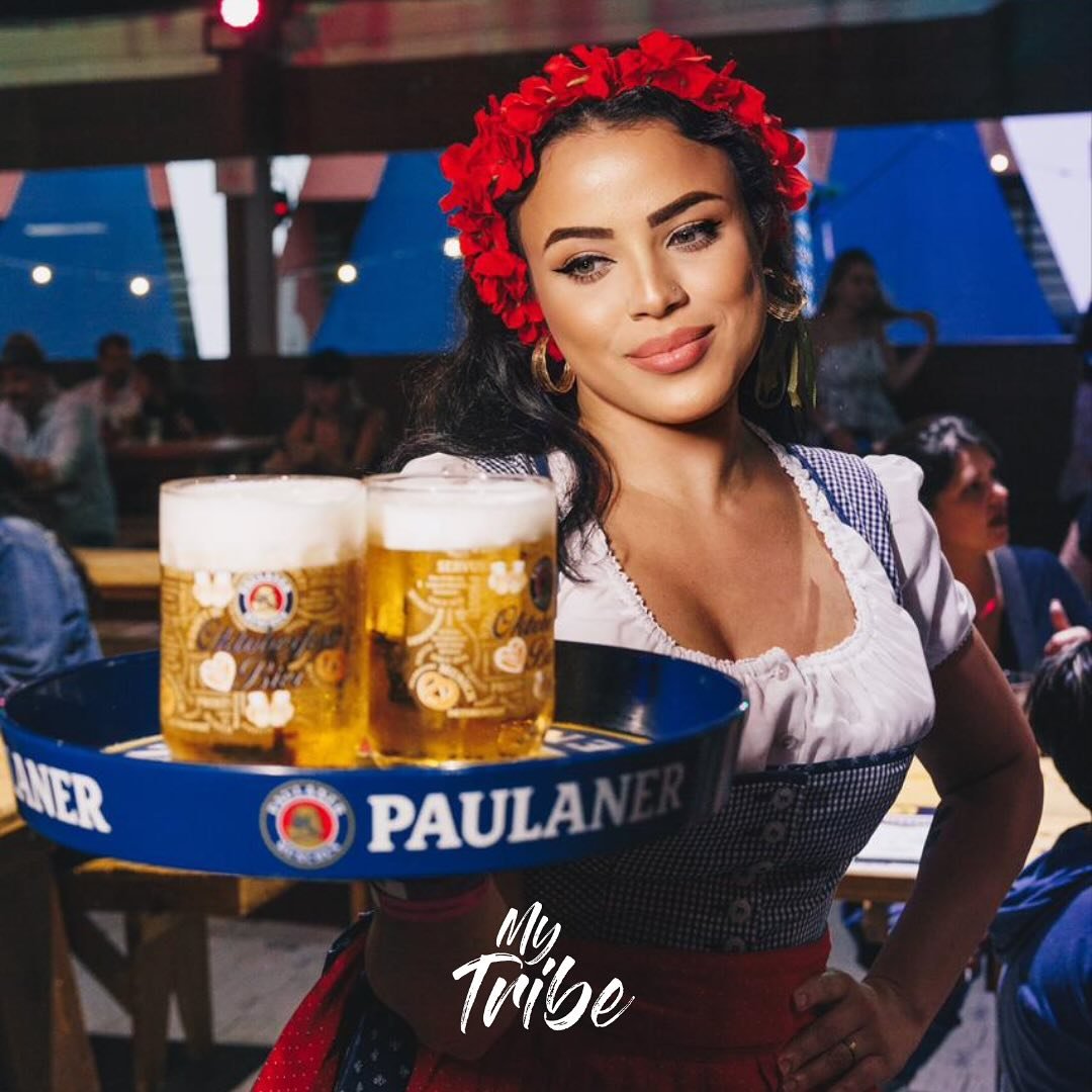 Promotora da My Tribe com traje típico servindo canecas de cerveja na Oktoberfest de São Paulo