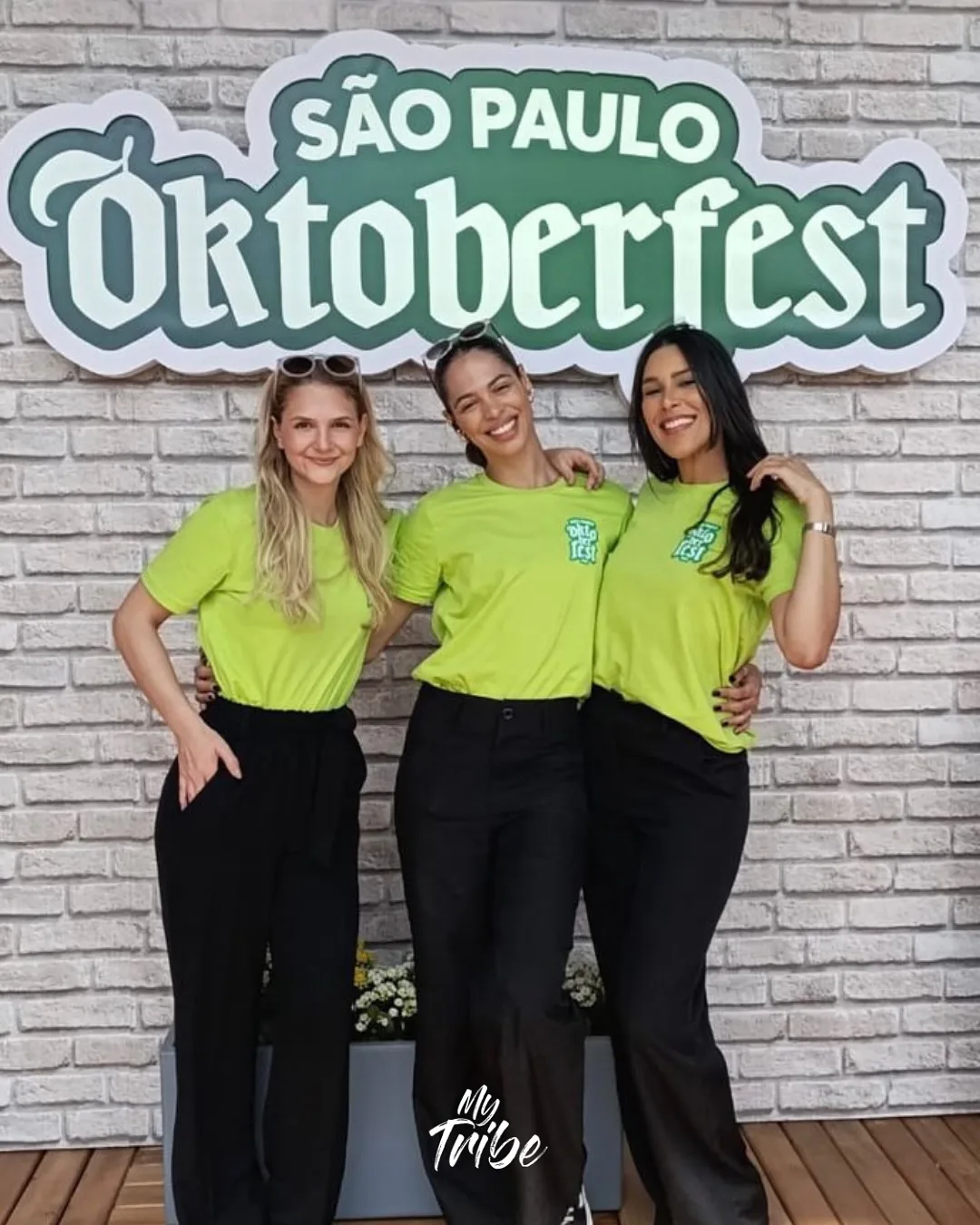 Três promotoras com camisetas verdes na São Paulo Oktoberfest