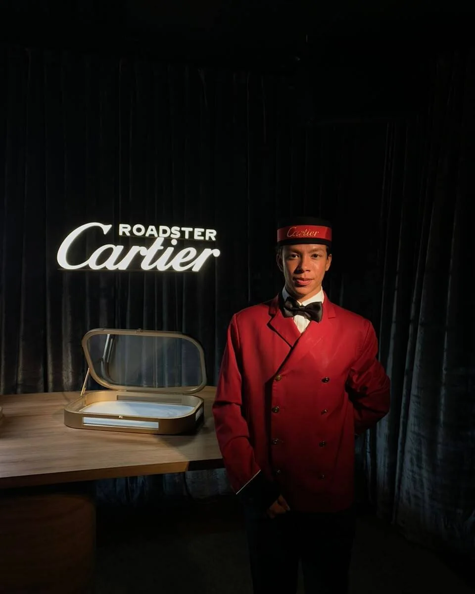 Recepcionista de uniforme vermelho e gravata borboleta em evento de lançamento de marca de luxo