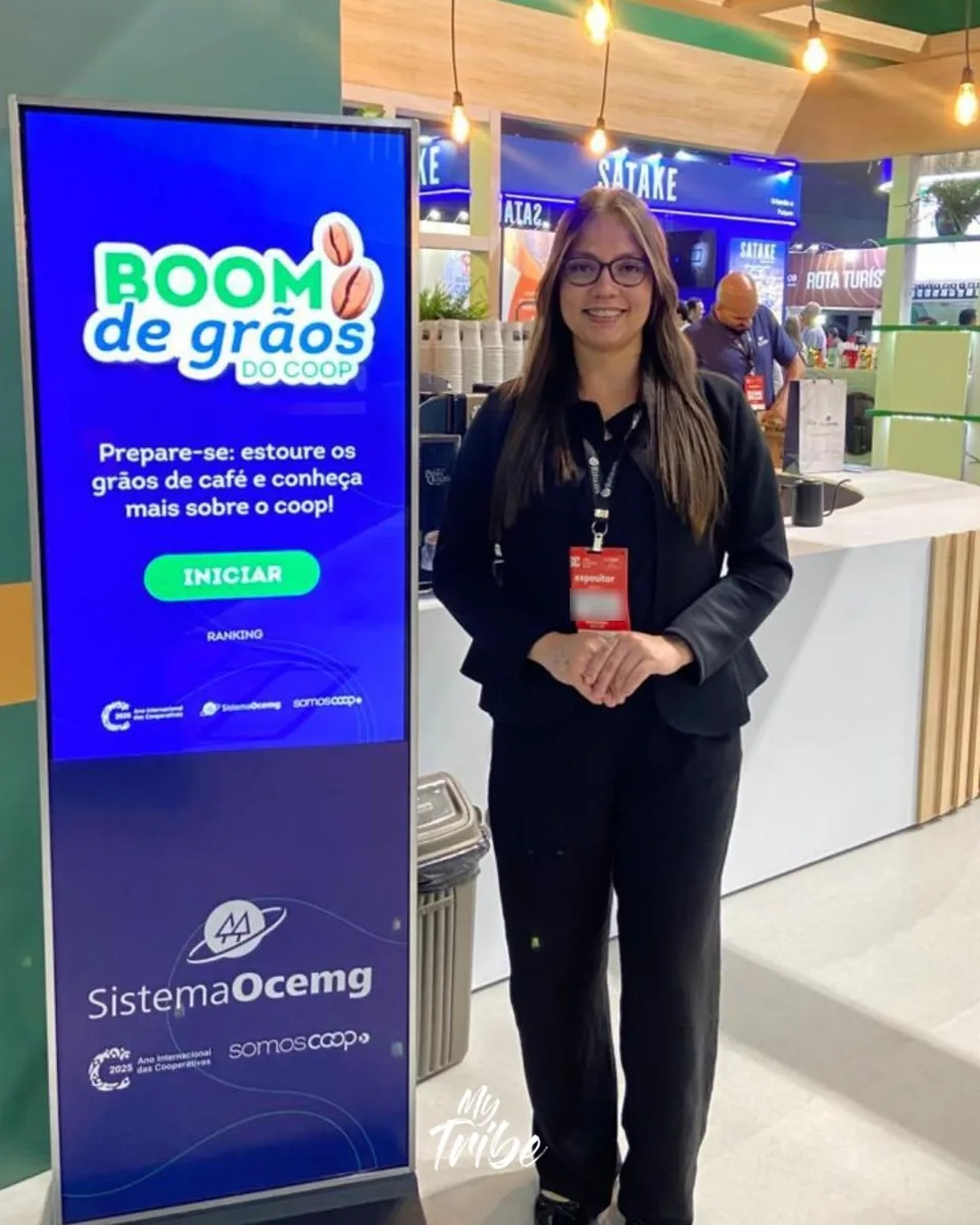 Profissional ao lado de totem com o jogo Boom de Grãos do Sistema Ocemg em feira